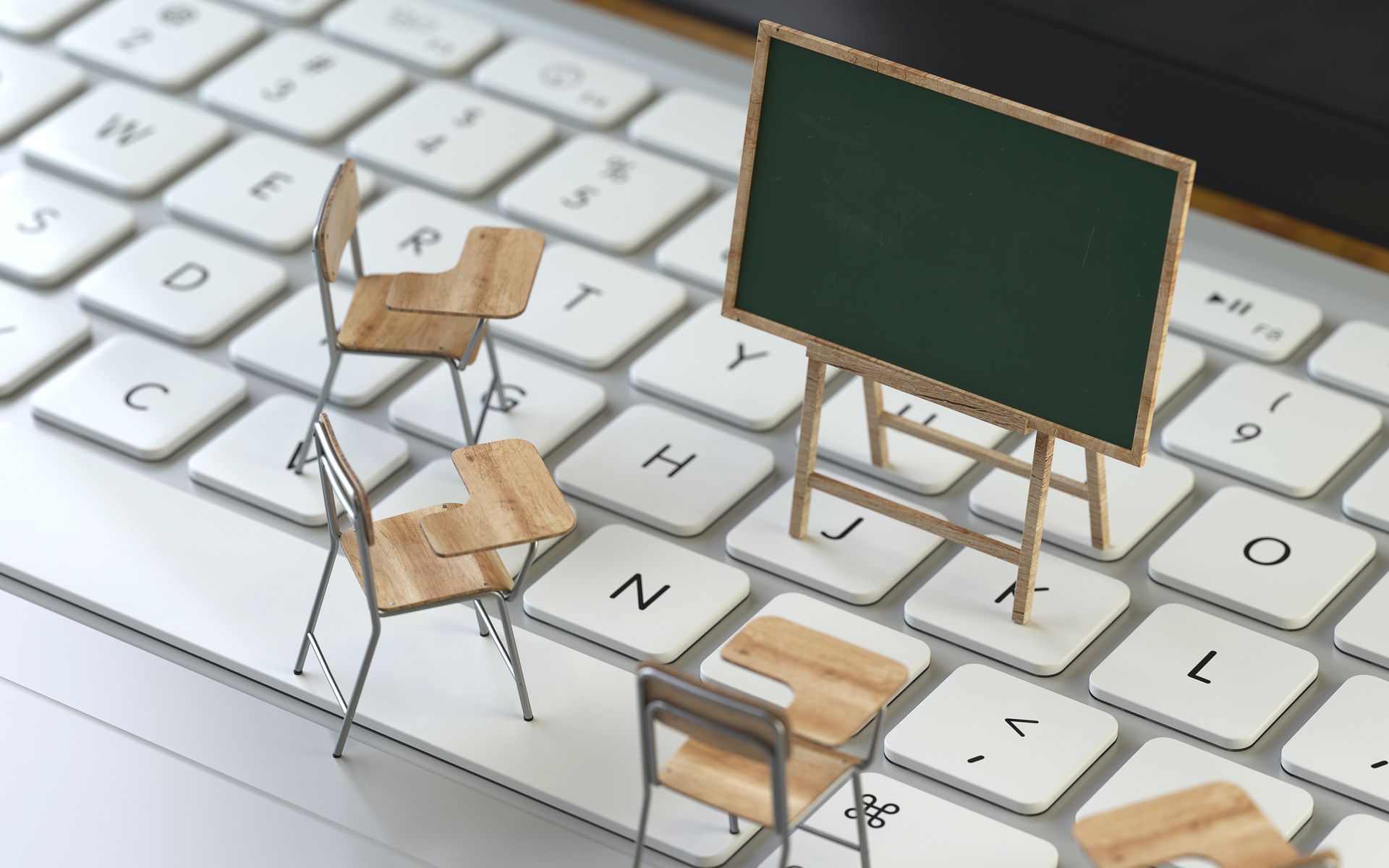 Foto von einer Tastatur, auf der Miniaturmodelle von einer Kreidetafel und St&uuml;hlen stehen.