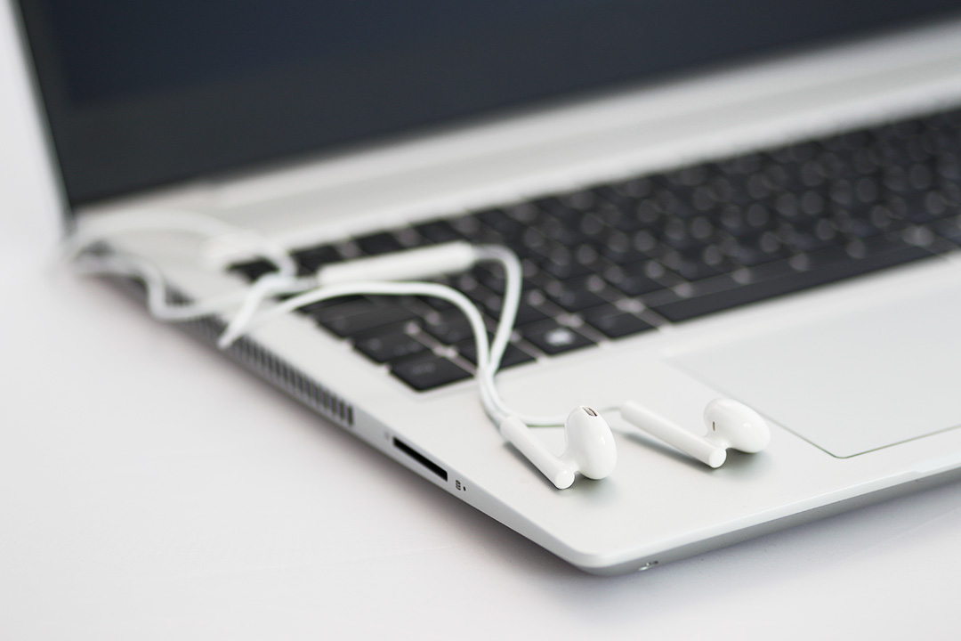Foto von auf einem Notebook liegenden In-Ear-Kopfh&ouml;rern.
