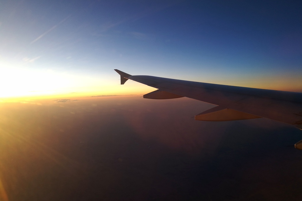 Flugreise: Ein Flugzeugfl&uuml;gel im Sonnenuntergang