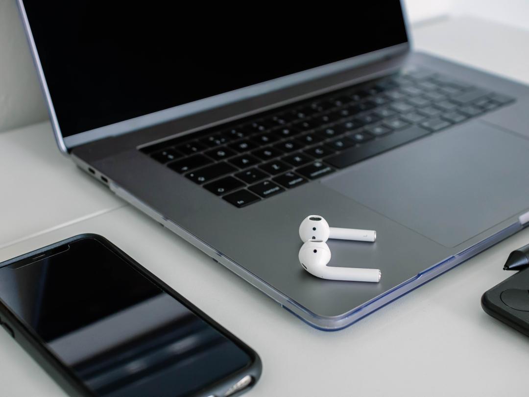 Foto von auf einem Notebook liegenden In-Ear-Kopfh&ouml;rern